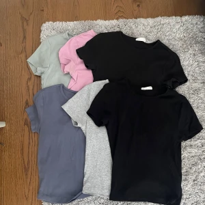 6-pack basic t-shirts Gina Tricot XS - Säljer ett 6-pack basic t-shirts från Gina Tricot i storlek XS, jag skulle säga att dem är ganska små i storleken. Färgerna är svart, grå, ljusgrön, rosa och blå. Alla har rund halsringning och korta ärmar. Den gråa tröjan har ett litet hål vid axeln men det tänker man inte på. Materialet är mjuk bomull som är skönt mot huden.