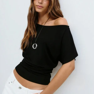 Svart offshoulder topp - Svart topp med offshoulder-design och korta, lösa ärmar. Modellen är croppad och har en bred resår i midjan som ger en snygg siluett. Mjuk och stretchig i materialet. Aldrig använda och prislappen kvar!💗💗