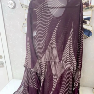 Lila beige kurdisk mönstrad klänning - Säljer en lång, flowy kurdisk klänning i transparent material med lila och beige vågiga ränder. Klänningen har vida ärmar och ett riktigt coolt, grafiskt mönster som sticker ut. Perfekt för dig som gillar statement-plagg och vill ha något unikt i garderoben. Passar storleken M och L✨