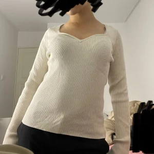 Vit ribbad tröja  - Säljer en vit ribbad långärmad tröja från Stockh LM Studio. Tröjan har en snygg v-ringad sweetheart-urringning och sitter figurnära. Perfekt till både jeans och kjol för en clean look.