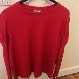 Röd långärmad tröja från C, 2XL - Snygg röd långärmad tröja från C i storlek 2XL. Tröjan har en enkel och stilren design med rund halsringning och lätt strukturerat tyg. Perfekt för dig som gillar en klassisk look med lite extra färg.