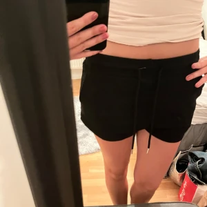 Svarta shorts med snörning  - Svarta mjuka shorts i storlek XS med elastisk midja och snörning framtill. De har en avslappnad passform och är perfekta för sommaren. Shortsen har fickor på sidorna och är gjorda i ett skönt bomullsmaterial.