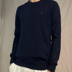 100% merinoullströja Polo Ralph Lauren - Snygg mörkblå tröja från Polo Ralph Lauren i tvättbar merinoull. Slim fit-modell med diskret broderad logga på bröstet. Klassisk rund halsringning och långa ärmar, perfekt för dig som gillar stilrena och bekväma plagg.