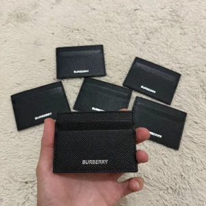 Svart korthållare från Burberry - Snyggt svart korthållare från Burberry i stilren design. Silvrig Burberry-logga framtill. Perfekt för att hålla koll på dina kort och cash utan att ta plats i fickan. Enkel och clean look som passar till allt.