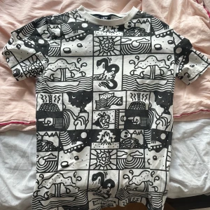 Lazy Oaf svartvit t-shirt med grafiskt tryck - Cool svartvit t-shirt från Lazy Oaf med unikt grafiskt mönster över hela plagget. T-shirten har korta ärmar och en avslappnad passform. Perfekt för dig som gillar statement-plagg och vill sticka ut i mängden.