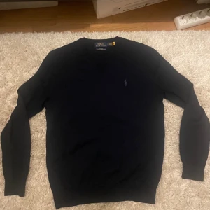 Mörkblå merinoullströja Polo Ralph Lauren - Snygg mörkblå tröja från Polo Ralph Lauren i tvättbar merinoull. Slim fit med v-ringning och broderad logga på bröstet. Perfekt för dig som gillar klassisk och stilren look. Långärmad och riktigt skön att bära. Inte använd någonting då den var för liten. Nypris 2400. Tveka inte med att höra av er om ni har funderingar. Pris kan diskuteras😃