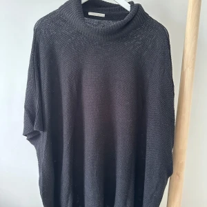 Svart stickad polotröja från Pieces - Oversized svart stickad polotröja från Pieces. Tröjan har en bred, mysig polokrage och är tillverkad i ett grovstickat material. Passformen är loose och ärmarna är kortare, vilket ger en avslappnad vibe. 