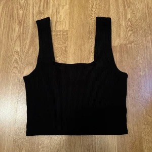 Svart topp - Svart basic kortare topp från H&M i storlek xs och är stretchig. I ett ribbat material. Fint skick! 