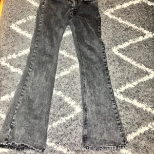 Grå bootcut jeans från Perfect Jeans - Snygga grå jeans från Perfect Jeans i bootcut-modell. Jeansen har klassisk femficksdesign, dragkedja och knapp i midjan. Materialet är tvättad denim som ger en cool vintagekänsla. Perfekta för dig som gillar en avslappnad men trendig look.