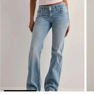 Nelly bootcut jeans - Snygga ljusblå jeans med bootcut passform och låg midja. Jeansen har coola bakfickor med rosa broderad zigzag-detalj. Fint skick, storlek 36. Nypris 699kr.  🌸✨