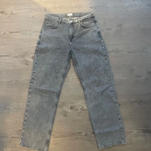 Grå straight jeans från Grunt - Säljer ett par gråa jeans från Grunt med klassisk femficksdesign och raka ben. Jeansen har en cool tvättad look, silverfärgad knapp och detaljerade sömmar. Passar dig som gillar en enkel men snygg stil och vill ha jeans som funkar till allt.
