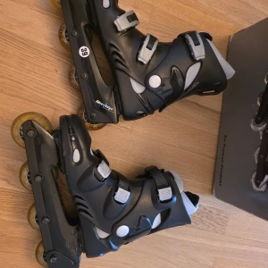 Svarta inlines storlek 39 - Säljer ett par svarta inlines från Silver Edge i storlek 39. De har grå och vita detaljer, tre spännen för extra stabilitet och gula hjul med ABEC3-kullager. Snygg och sportig design som passar dig som gillar fart och rörelse.