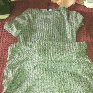 Grå ribbad kortklänning från H&M Divided - Säljer en grå ribbad kortklänning från H&M Divided i storlek 44. Klänningen har korta ärmar och rund hals, med ett snyggt vertikalt ribbat mönster som ger en chill vibe. Perfekt för dig som gillar enkel och stilren look.