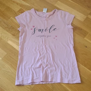 Rosa t-shirt med text från KappAhl - Söt ljusrosa pyjamastopp från KappAhl med trycket 'smile and follow your dreams'. Storlek 170, men passar XS. 