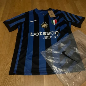 Inter Milan home - Inter Milan matchtröja från Nike med klassiska blå och svarta ränder, korta ärmar och Dri-Fit material. Framsidan har klubbmärke, sponsortryck och italienska mästerskapsmärket. Baksidan har U-Power logga. Perfekt för dig som vill representera Inter.