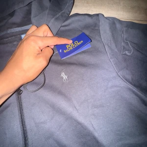 Mörkblå  hoodie från Polo Ralph Lauren - Skriv om du vill ha mer bilder. Inte polyester!!!!!!!! Helt ny Snygg mörkblå hoodie från Polo Ralph Lauren den var lite för stor för mig med klassisk logga broderad på bröstet. Hoddien har huva med snörning, dragkedja framtill och två fickor. Tillverkad i mjuk bomull som är skön att ha på sig. Perfekt för chill dagar och streetwear.