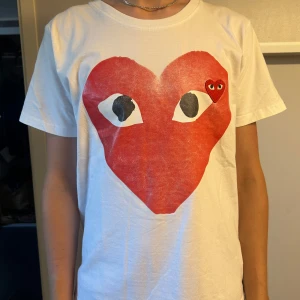 Vit Comme des Garçons Play t-shirt - Säljer en vit t-shirt från Comme des Garçons. Skicket är väldigt bra då den knappt är använd. Fortfarande ett väldigt frächst plagg. Den är i storlek S. 