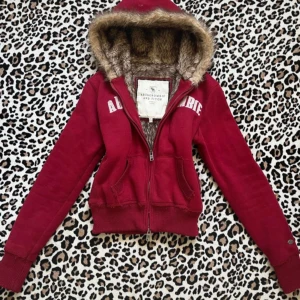Röd abercrombie and fitch päls hoodie - Super fin röd hoodie med pälsluva från abercrombie & fitch, bra skick utom att dragkedjan fastnar lite, strl XL på lappen fast sitter som mycket mindre som man ser på bild 4 