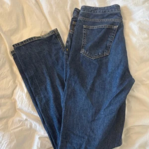 Blå low waist straight jeans, 29/33 - Säljer ett par blå jeans med låg midja och raka ben. Klassisk femficksmodell med knapp och dragkedja framtill. Snygg mörkblå tvätt och normal passform, perfekta till en chill outfit. Materialet är jeans och insidan visar 'LOW STRAIGHT WAIST 29 LENGTH 33'.