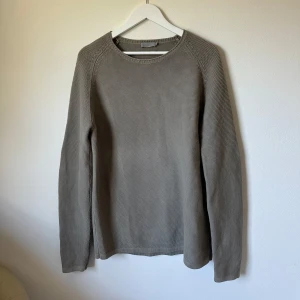 Grå stickad tröja från COS - Säljer en stilren grå stickad tröja från COS i storlek M. Tröjan har rund hals, långärmade ärmar och är gjord i mjuk bomull. Perfekt för lager-på-lager och chill dagar. Enkel design utan mönster eller detaljer, passar dig som gillar minimalistisk stil. 1C8