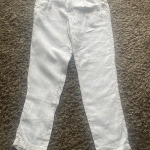 Vita linnebyxor från Zara, strl 40 - Fräscha vita linnebyxor från Zara i storlek 40. Byxorna har rak passform och är tillverkade i ett lätt och luftigt linnematerial, perfekt för varma dagar. Använt en del men inga skador