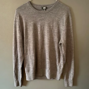 Grå stickad tröja från Uniqlo - En enkel och stilren grå stickad tröja från Uniqlo. Tröjan har rund hals, långa ärmar och ribbade muddar vid hals, ärmslut och nederkant. Perfekt för lager-på-lager och passar dig som gillar minimalistisk stil. Ny pris 599 