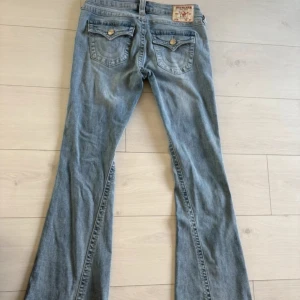 True Religion Joey Low Rise Flare  - Säljer ett par ljusblå jeans från True Religion, modell Joey Low Rise Flare. Helt nya utan prislapp men säljer pågrund av att de är alldeles för stora
