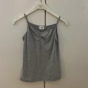 Grå linnetopp från bpc collection - Snygg grå linnetopp från bpc collection med smala axelband och lätt v-ringad hals. Mjuk och skön känsla, perfekt för varma dagar. Enkel design som funkar till jeans eller shorts. Materialet är bomull och toppen har en normal passform.
