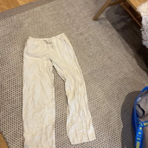 Beige linnebyxor från Gina Tricot - Snygga och luftiga beige linnebyxor från Gina Tricot med rak passform och elastisk midja med snörning. Perfekta för chill dagar och sommarhäng. Materialet är linne som ger en skön och sval känsla. Passar dig som gillar enkel och clean stil.