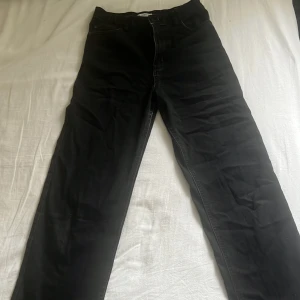 Svarta raka jeans från Lindex - Svarta jeans från Lindex med klassisk femficksdesign och raka ben. Jeansen har hög midja och är tillverkade i ett mjukt bomullsmaterial med lite stretch. Snygga att matcha med sneakers eller boots för en chill look.