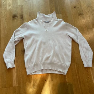 Beige stickad tröja med half zip från Zara - Snygg beige stickad tröja från Zara med hög krage och half zip framtill. Tröjan har långärmade ärmar och ribbade muddar vid hals, ärmslut och nederkant. Perfekt för dig som gillar stilrena och enkla plagg med en modern touch.