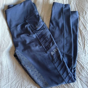 Mörkblåa ridtights från Ariat - Snygga mörkblå leggings från Ariat. De har praktiska fickor med dragkedja på sidorna och logga på benet. Materialet är stretchigt syntet, perfekt för ridning eller träning. De är i väldigt fint skick då jag inte använt de mycket. Använd gärna köp nu och hör av er vid frågor!💓