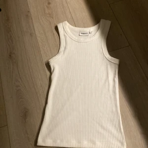 Vit ribbad linnetopp från Kappahl XS - Fräsch vit linnetopp från Kappahl i storlek XS. Modellen är ribbad och har en klassisk ärmlös design med rund hals. Perfekt att styla med jeans eller shorts för en chill look. Materialet är mjukt och stretchigt, vilket gör den superbekväm att bära.
