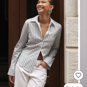 Vit randig skjorta från Nelly - Snygg slutsåld vit skjorta med svarta vertikala ränder från Nelly. Modellen har klassisk krage, långa ärmar och knappar framtill. Skjortan är något insydd i midjan vilket ger en lite mer "snatched" look. Aldrig använd, prislappen kvar, har själv xs & skulle beskriva storleken som en M