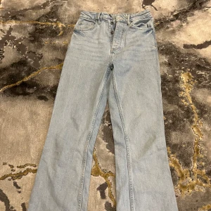 Ljusblå bootcut jeans från Bikbok - Säljer ett par ljusblå jeans från Bikbok  med bootcut passform och hög midja. Klassisk femficksdesign, knappgylf och läderpatch bak i midjan. Jeansen är tillverkade i jeansmaterial och har en clean look som passar till sneakers eller boots.