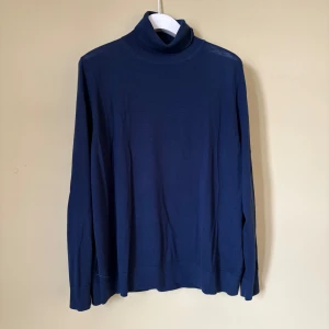 Marinblå polotröja i merinoull M&S - Säljer en stilren marinblå polotröja från M&S Collection, tillverkad i extra fin merinoull. Tröjan har lång ärm och klassisk polokrage, perfekt för dig som gillar en clean och tidlös look. Passar dig som vill ha något mjukt och skönt med lite lyxig känsla.