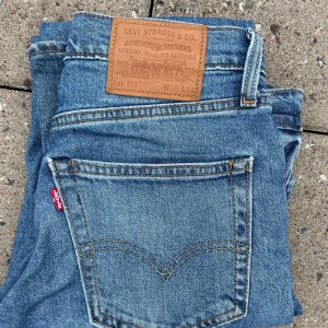 Levi's 511 blå jeans W30 L34 - Säljer ett par klassiska blå Levi's 511 jeans med normal passform och raka ben. Jeansen har fem fickor, knappgylf och den ikoniska läderpatchen bak i midjan. Perfekta för dig som gillar tidlös denimstil. Vid frågor hör av dig.