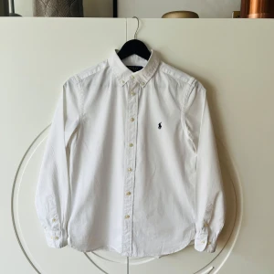 Vit Ralph Lauren skjorta - Säljer en klassisk vit skjorta från Ralph Lauren i slim fit. Skjortan är i nyskick och använd ett fåtal gånger. Nypris för skjortan ligger runt 1000kr.