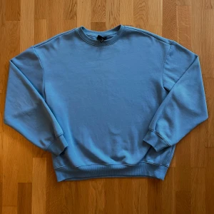 Ljusblå sweatshirt - Säljer en enkel och stilren ljusblå sweatshirt med rund halsringning. Perfekt för en avslappnad och bekväm stil.