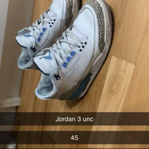 Jordan 3 UNC sneakers - Säljer ett par Nike Air Jordan 3 UNC sneakers i vitt med ljusblå och grå detaljer. Skorna har klassisk rund tå, snörning och mönstrad sula. Perfekta för dig som gillar streetwear och vill sticka ut med en ikonisk modell.