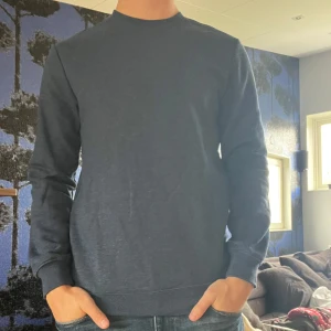 Mörkblå långärmad tröja - Säljer en stilren mörkblå långärmad tröja med rund hals. Tröjan har en enkel design utan synliga loggor eller mönster och är perfekt för en clean och avslappnad look. Mjuk och skön känsla, passar till det mesta.