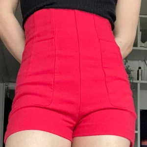 Röda högmidjade shorts - OBS!! ALLA MINA PLAGG GRATIS VID UPPHÄTMNING I RÅCKSTA!!! Snygga röda shorts med väldigt hög midja och figurnära passform. Stora framfickor, men bakfickorna är fejk. Går att dra upp dragkedjan på mig som är storlek S, men inte bekväma för långa stunder att sitta eller röra sig i, skulle därav säga storlek XS. Ganska tjockt, stabilt, kvalitativt tyg, så inte jättebra för aktivitet utan mer finare tillfällen. 