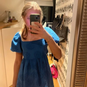 Blå klänning med puffärmar från Meet Me There - Supersöt blå klänning från Meet Me There med puffiga kortärmar och broderat hålmönster. Klänningen har öppen rygg och markerad midja.kläningen är använd en gång i tre timmar på en skolavslutning så det är i nyskick 