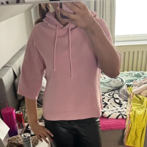 Ljusrosa hoodie med korta ärmar - Säljer en ljusrosa hoodie med korta ärmar och huva med dragsko. Perfekt för dig som vill ha en avslappnad och trendig look. Passar bra till både jeans och leggings.