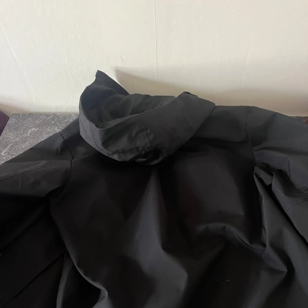 Säljer en svart skaljacka från Arc'teryx i storlek M. Jackan har huva, dragkedja framtill och GORE-TEX-material som gör den perfekt för blåsiga och regniga dagar. Snygg och funktionell med logga på bröstet och ärmficka.. Takit.