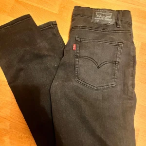Svarta jeansbyxor från Levi's 511 - Säljer ett par svarta Levi's 511 jeans med klassisk femficksdesign och raka ben. Byxorna har normal passform och är tillverkade i jeansmaterial. Perfekta för dig som gillar stilrena och tidlösa jeans.