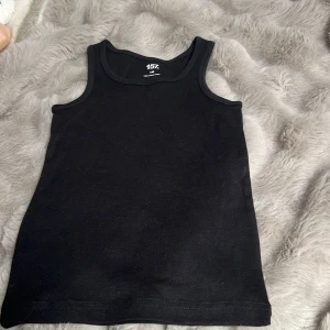 Svart linnetopp från 157 - Säljer en enkel och stilren svart linnetopp från 157 i 100% ekologisk bomull. Perfekt för varma dagar eller som lager under andra plagg. Klassisk passform med rund halsringning.