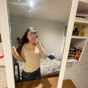 Beige långärmad topp med fyrkantig ringning - Säljer en beige långärmad topp med snygg fyrkantig ringning. Toppen är figurnära och passar perfekt till jeans eller kjol. Enkel och stilren design som är lätt att matcha med olika outfits. 