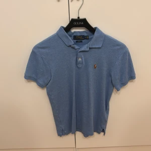 Ljusblå pikétröja från Polo Ralph Lauren - Säljer en ljusblå pikétröja från Polo Ralph Lauren i slim fit-modell. Fint skick. 