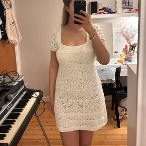 Vit stickad klänning från Zara - Supersöt vit stickad klänning från Zara med kort ärm och fyrkantig ringning. Klänningen har ett vackert hålmönster och sitter figurnära utan att vara tight. Perfekt för sommarens alla tillfällen! Endast använd 1 gång! 